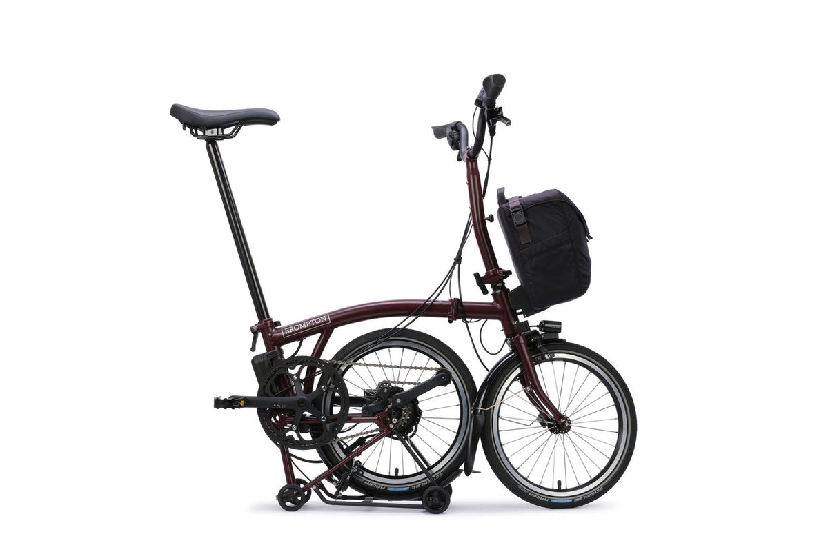 Brompton Electric C Line in plum red — mid-fold with the rear wheel tucked under