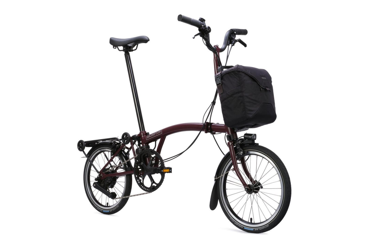 Brompton Electric C Line in plum red — three-quarter view with front bag