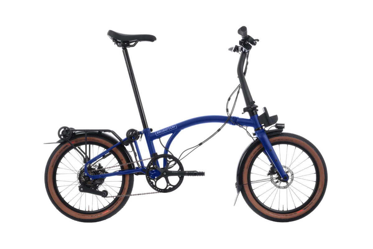 Brompton Electric G Line in Brompton blue — full side view with tan-wall tyres and rear rack