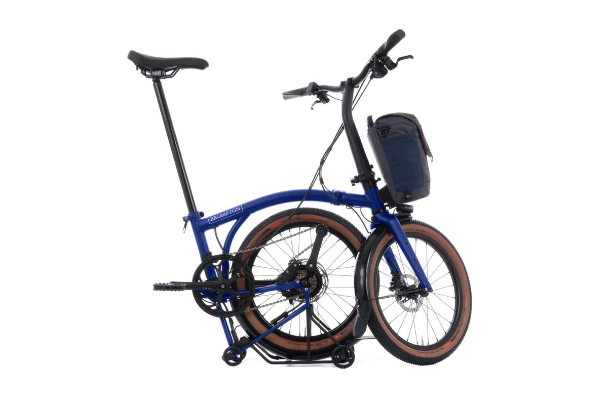 Brompton Electric G Line in Brompton blue — mid-fold with the rear wheel tucked under