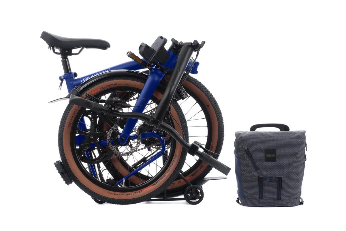 Brompton Electric G Line in Brompton blue — fully folded beside the front bag