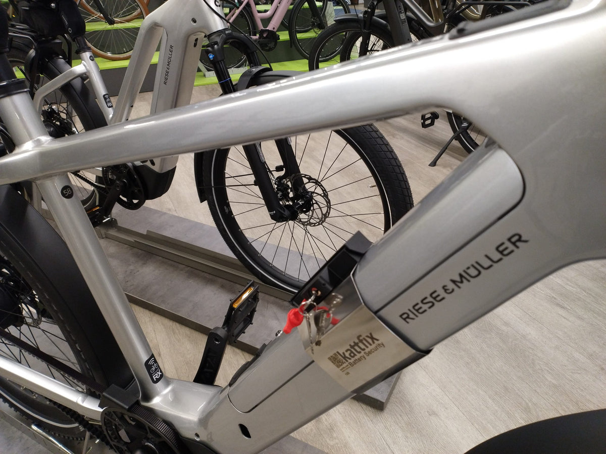 Kattfix battery lock fitted around the downtube battery of a silver Riese & Muller Charger in the shop
