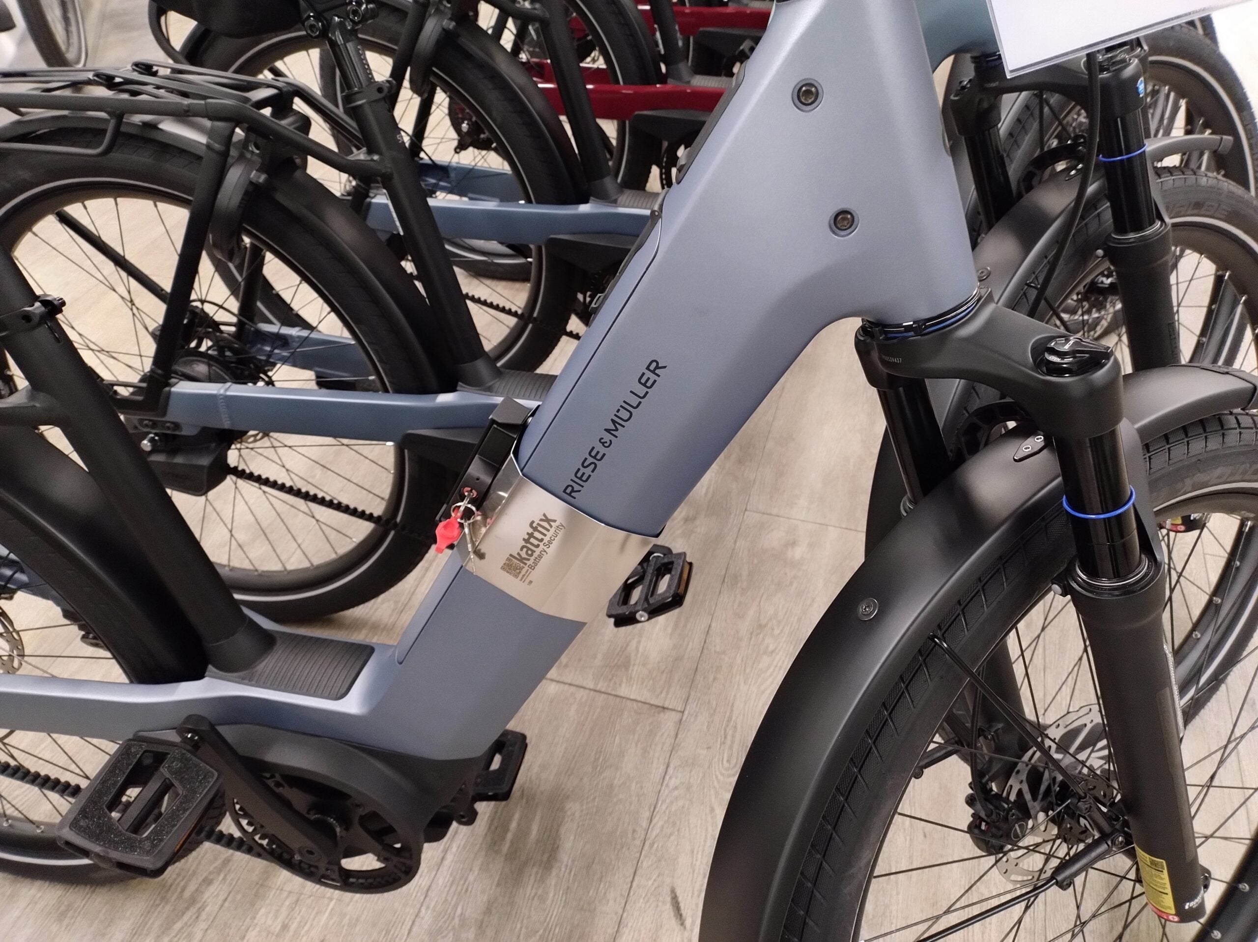 Blue-grey Riese & Muller Nevo in the shop with a Kattfix lock fitted to its downtube battery